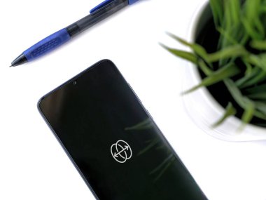 Lod, Israel - 8 Temmuz 2020: Reface uygulamasının beyaz arka planda logosu olan siyah cep telefonlu modern minimalist ofis çalışma alanı. Üst görünüm yatağını kapat.