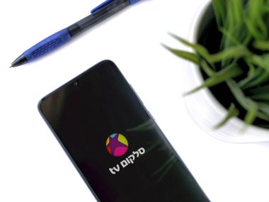 Lod, Israel - 8 Temmuz 2020: Modern minimalist ofis çalışma alanı, beyaz arka planda logosu olan cep telefonlu akıllı cep telefonu uygulaması fırlatma ekranı. Üst görünüm yatağını kapat.