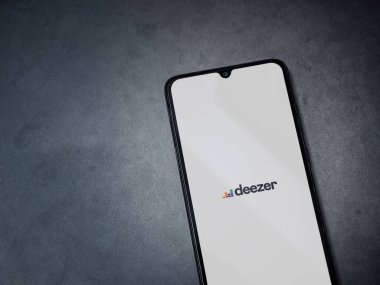 Lod, Israel - 8 Temmuz 2020: Deezer Music Player uygulama ekranı koyu mermer taşlı arka planda siyah bir cep telefonunun logosu var. Üst görünüm düzlüğü kopyalama alanı ile yatıyordu.