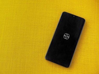 Lod, Israel - 8 Temmuz 2020: Sarı kumaş arka planda siyah bir cep telefonunun logosu ile uygulama fırlatma ekranını yansıt. Üst görünüm düzlüğü kopyalama alanı ile yatıyordu.