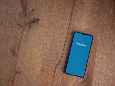 Lod, Israel - 8 Temmuz 2020: PayBox uygulama ekranı üzerinde siyah bir cep telefonunun amblemi olan tahta arka planda. Üst görünüm düzlüğü kopyalama alanı ile yatıyordu.