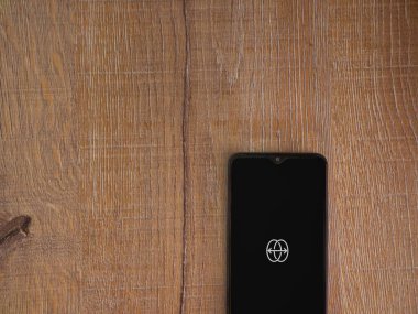 Lod, Israel - 8 Temmuz 2020: Ahşap arka planda siyah bir cep telefonunun logosu ile uygulama fırlatma ekranını yansıt. Üst görünüm düzlüğü kopyalama alanı ile yatıyordu.