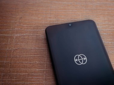 Lod, Israel - 8 Temmuz 2020: Ahşap arka planda siyah bir cep telefonunun logosu ile uygulama fırlatma ekranını yansıt. Üst görünüm düzlüğü kopyalama alanı ile yatıyordu.