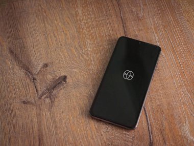 Lod, Israel - 8 Temmuz 2020: Ahşap arka planda siyah bir cep telefonunun logosu ile uygulama fırlatma ekranını yansıt. Üst görünüm düzlüğü kopyalama alanı ile yatıyordu.