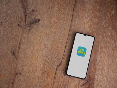 Lod, Israel - 8 Temmuz 2020: Radius 100FM uygulama ekranı ve üzerinde logo bulunan siyah bir cep telefonu ahşap arka planda. Üst görünüm düzlüğü kopyalama alanı ile yatıyordu.