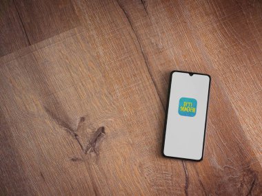 Lod, Israel - 8 Temmuz 2020: Radius 100FM uygulama ekranı ve üzerinde logo bulunan siyah bir cep telefonu ahşap arka planda. Üst görünüm düzlüğü kopyalama alanı ile yatıyordu.