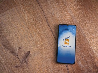 Lod, Israel - 8 Temmuz 2020: İsrail Elektrik Şirketi uygulama ekranı İbranice metinde logosu olan ahşap arka planda siyah bir cep telefonu görüntüsü. Üst görünüm düzlüğü kopyalama alanı ile yatıyordu.