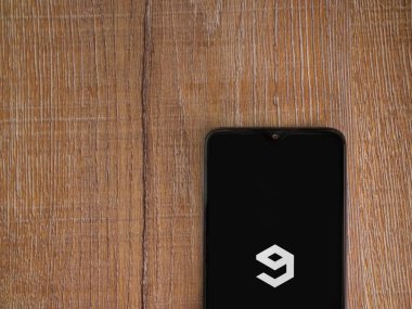 Lod, Israil - 8 Temmuz 2020: 9GAG uygulama ekranıyla birlikte ahşap arka planda siyah bir cep telefonu sergilenmektedir. Üst görünüm düzlüğü kopyalama alanı ile yatıyordu.