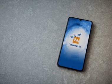Lod, Israel - 8 Temmuz 2020: Israel Electric Corporation uygulama ekranı seramik taş zemin üzerinde siyah bir cep telefonunun logosu İbranice metinde. Üst görünüm düzlüğü kopyalama alanı ile yatıyordu.