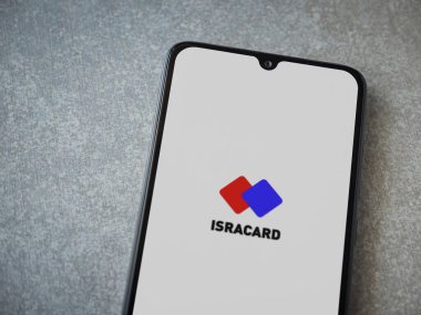 Lod, Israel - 8 Temmuz 2020: Seramik taş zemin üzerinde siyah bir cep telefonunun logosu olan Isracard uygulaması fırlatma ekranı. Üst görünüm düzlüğü kopyalama alanı ile yatıyordu.