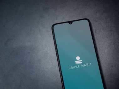 Lod, Israel - 8 Temmuz 2020: Basit Alışkanlık uygulama başlatma ekranı koyu mermer taşlı arka planda siyah bir cep telefonunun logosu. Üst görünüm düzlüğü kopyalama alanı ile yatıyordu.