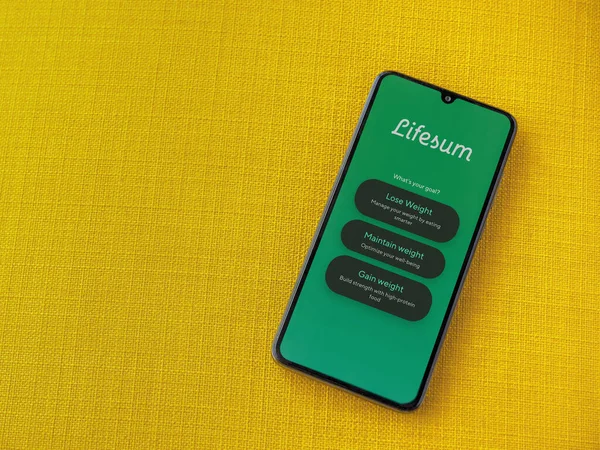 Lod, Israel - 8 Temmuz 2020: Sarı kumaş arka planda siyah bir cep telefonunun logosu olan Lifesum uygulaması fırlatma ekranı. Üst görünüm düzlüğü kopyalama alanı ile yatıyordu.