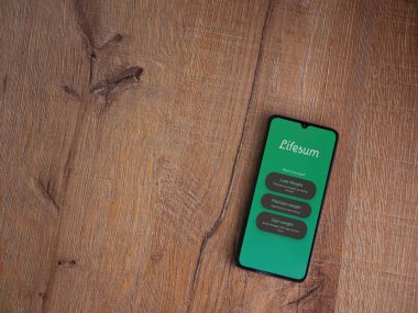 Lod, Israel - 8 Temmuz 2020: Lifesum uygulama ekranıyla ahşap arka planda siyah bir cep telefonunun logosu görülüyor. Üst görünüm düzlüğü kopyalama alanı ile yatıyordu.