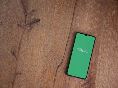 Lod, Israel - 8 Temmuz 2020: Lifesum uygulama ekranıyla ahşap arka planda siyah bir cep telefonunun logosu görülüyor. Üst görünüm düzlüğü kopyalama alanı ile yatıyordu.