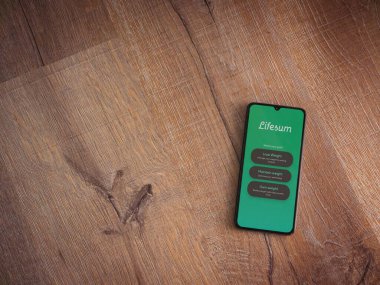 Lod, Israel - 8 Temmuz 2020: Lifesum uygulama ekranıyla ahşap arka planda siyah bir cep telefonunun logosu görülüyor. Üst görünüm düzlüğü kopyalama alanı ile yatıyordu.