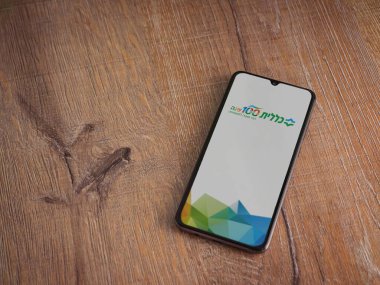 Lod, Israel - 8 Temmuz 2020: Clalit Sağlık Hizmetleri uygulama ekranı İbranice metinlerle siyah bir cep telefonunun ahşap arka planda sergilenmesi ile başlatıldı. Üst görünüm düzlüğü kopyalama alanı ile yatıyordu.