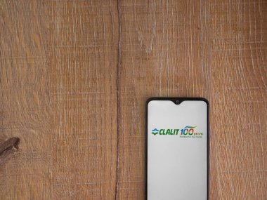 Lod, Israel - 8 Temmuz 2020: Clalit Sağlık Hizmetleri uygulama ekranı üzerinde siyah bir cep telefonunun ahşap arka planda sergilendiği logo. Üst görünüm düzlüğü kopyalama alanı ile yatıyordu.