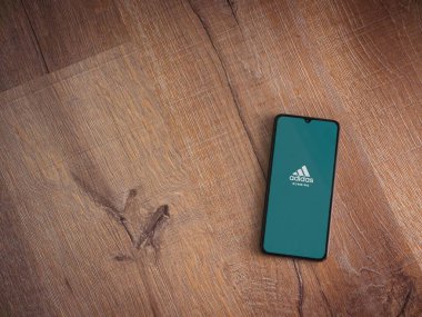 Lod, Israel - 8 Temmuz 2020: Adidas Running app fırlatma ekranı üzerinde logo bulunan siyah bir cep telefonu ahşap arka planda. Üst görünüm düzlüğü kopyalama alanı ile yatıyordu.