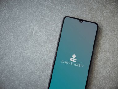 Lod, Israel - 8 Temmuz 2020: Seramik taş zemin üzerinde siyah bir cep telefonunun logosu olan Basit Alışkanlık uygulaması başlatma ekranı. Üst görünüm düzlüğü kopyalama alanı ile yatıyordu.