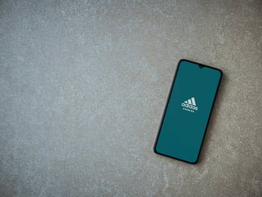 Lod, Israel - 8 Temmuz 2020: Adidas Run uygulaması seramik taş zemin üzerinde siyah bir cep telefonunun logosu olan fırlatma ekranı. Üst görünüm düzlüğü kopyalama alanı ile yatıyordu.