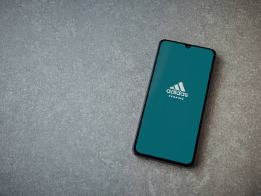 Lod, Israel - 8 Temmuz 2020: Adidas Run uygulaması seramik taş zemin üzerinde siyah bir cep telefonunun logosu olan fırlatma ekranı. Üst görünüm düzlüğü kopyalama alanı ile yatıyordu.