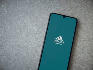 Lod, Israel - 8 Temmuz 2020: Adidas Run uygulaması seramik taş zemin üzerinde siyah bir cep telefonunun logosu olan fırlatma ekranı. Üst görünüm düzlüğü kopyalama alanı ile yatıyordu.