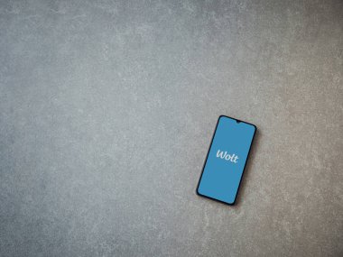 Lod, Israel - 8 Temmuz 2020: Seramik taş zemin üzerinde siyah bir cep telefonunun logosu olan Wolt uygulaması fırlatma ekranı. Üst görünüm düzlüğü kopyalama alanı ile yatıyordu.