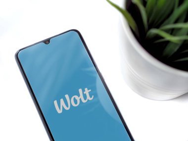 Lod, Israel - 8 Temmuz 2020: Beyaz arkaplan üzerinde Wolt uygulaması olan siyah cep telefonlu modern minimalist ofis çalışma alanı. Üst görünüm yatağını kapat.