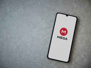Lod, Israel - 8 Temmuz 2020: MeGA uygulama başlatma ekranı seramik taş zemin üzerinde siyah bir cep telefonunun logosu. Üst görünüm düzlüğü kopyalama alanı ile yatıyordu.