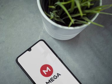 Lod, Israel - 8 Temmuz 2020: MeGA uygulama ekranlı ve mermer zemin üzerinde logosu olan siyah cep telefonlu modern minimalist ofis çalışma alanı. Üst görünüm düzlüğü kopyalama alanı ile yatıyordu.