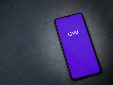 Lod, Israel - 8 Temmuz 2020: LiveU uygulama ekranıyla koyu mermer taşlı arka planda siyah bir cep telefonunun logosu görülüyor. Üst görünüm düzlüğü kopyalama alanı ile yatıyordu.