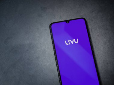 Lod, Israel - 8 Temmuz 2020: LiveU uygulama ekranıyla koyu mermer taşlı arka planda siyah bir cep telefonunun logosu görülüyor. Üst görünüm düzlüğü kopyalama alanı ile yatıyordu.