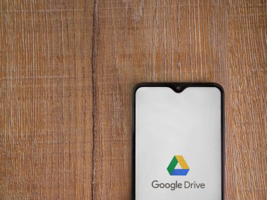 Lod, Israel - 8 Temmuz 2020: Google Drive uygulama ekranıyla birlikte tahta arka planda siyah bir cep telefonunun logosu görülüyor. Üst görünüm düzlüğü kopyalama alanı ile yatıyordu.