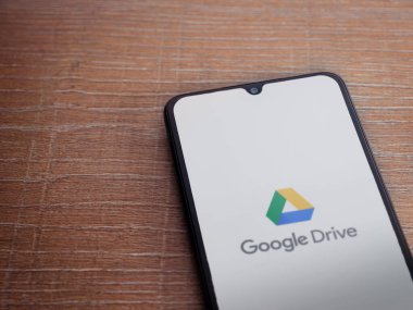 Lod, Israel - 8 Temmuz 2020: Google Drive uygulama ekranıyla birlikte tahta arka planda siyah bir cep telefonunun logosu görülüyor. Üst görünüm düzlüğü kopyalama alanı ile yatıyordu.