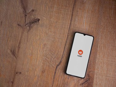 Lod, Israel - 8 Temmuz 2020: Ahşap arka planda siyah bir cep telefonunun logosu olan Reddit uygulaması fırlatma ekranı. Üst görünüm düzlüğü kopyalama alanı ile yatıyordu.