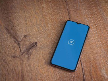 Lod, Israel - 8 Temmuz 2020: Ahşap arka planda siyah bir cep telefonunun logosu olan hızlı mesaj uygulaması fırlatma ekranı. Üst görünüm düzlüğü kopyalama alanı ile yatıyordu.