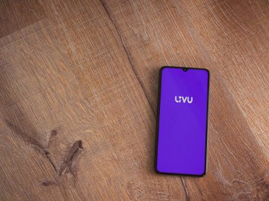 Lod, Israel - 8 Temmuz 2020: LiveU uygulama ekranı üzerinde logo olan siyah bir cep telefonu ahşap arka planda. Üst görünüm düzlüğü kopyalama alanı ile yatıyordu.