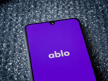 Lod, Israel - 8 Temmuz 2020: Ablo uygulama ekranıyla metalik arka planda siyah bir cep telefonunun logosu görülüyor. Üst görünüm yatağını kapat.