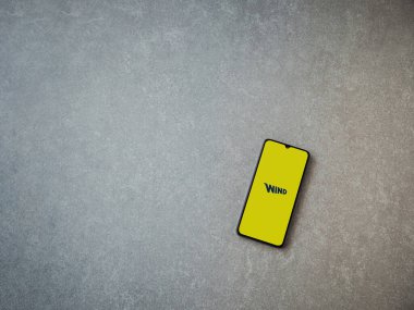 Lod, Israel - 8 Temmuz 2020: Seramik taş zemin üzerinde siyah bir cep telefonunun logosu olan Rüzgâr uygulaması fırlatma ekranı. Üst görünüm düzlüğü kopyalama alanı ile yatıyordu.