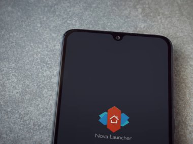 Lod, Israel - 8 Temmuz 2020: Nova Launcher uygulaması seramik taş zemin üzerinde siyah bir cep telefonunun logosu olan fırlatma ekranı. Üst görünüm düzlüğü kopyalama alanı ile yatıyordu.