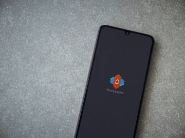 Lod, Israel - 8 Temmuz 2020: Nova Launcher uygulaması seramik taş zemin üzerinde siyah bir cep telefonunun logosu olan fırlatma ekranı. Üst görünüm düzlüğü kopyalama alanı ile yatıyordu.