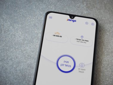 Lod, Israel - 8 Temmuz 2020: Pango uygulaması seramik taştan arka planda siyah bir cep telefonunun logosu İbranice metin ile çalıştırma ekranı. Üst görünüm düzlüğü kopyalama alanı ile yatıyordu.