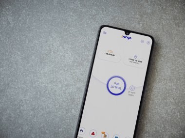 Lod, Israel - 8 Temmuz 2020: Pango uygulaması seramik taştan arka planda siyah bir cep telefonunun logosu İbranice metin ile çalıştırma ekranı. Üst görünüm düzlüğü kopyalama alanı ile yatıyordu.