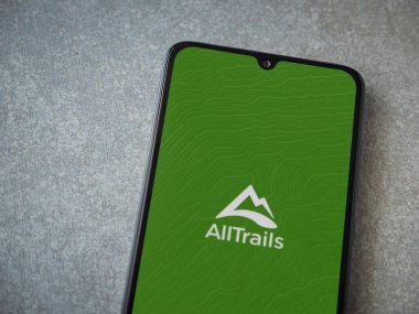 Lod, Israel - 8 Temmuz 2020: Seramik taş zemin üzerinde siyah bir cep telefonunun logosu olan AllTrails uygulama ekranı. Üst görünüm düzlüğü kopyalama alanı ile yatıyordu.