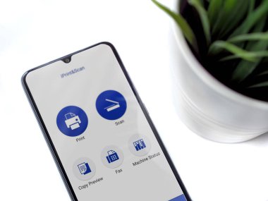 Lod, Israel - 8 Temmuz 2020: Siyah cep telefonlu modern minimalist ofis çalışma alanı İPrint & Scan uygulaması çalıştırma ekranı beyaz arkaplanda. Üst görünüm düzlüğü kopyalama alanı ile yatıyordu.