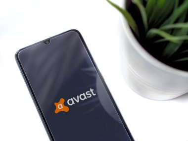 Lod, Israel - 8 Temmuz 2020: Beyaz arka planda logosu olan Avast Antivirüs uygulama ekranlı siyah cep telefonlu modern minimalist ofis çalışma alanı. Üst görünüm düzlüğü kopyalama alanı ile yatıyordu.