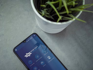 Lod, Israel - 8 Temmuz 2020: İsrail Demiryolları uygulamalı siyah cep telefonlu modern minimalist ofis çalışma alanı mermer zemin üzerinde İbranice metin logosu olan uygulama ekranı. Üst görünüm düzlüğü kopyalama alanı ile yatıyordu.