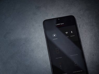 Lod, Israel - 8 Temmuz 2020: Panasonic LUMIX Sync uygulama ekranıyla koyu mermer taşlı arka planda siyah bir mobil akıllı telefon görüntüsü. Üst görünüm düzlüğü kopyalama alanı ile yatıyordu.