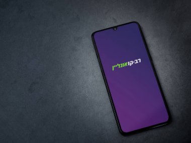 Lod, Israel - 8 Temmuz 2020: Rav Kav Online uygulama ekranı koyu renkli mermer taşlı arka planda siyah bir cep telefonunun logosu İbranice metin ile başlatıldı. Üst görünüm düzlüğü kopyalama alanı ile yatıyordu.