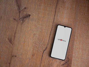 Lod, Israel - 8 Temmuz 2020: Ahşap arka planda siyah bir cep telefonunun logosu olan uygulamayı çalıştırma ekranını aydınlat. Üst görünüm düzlüğü kopyalama alanı ile yatıyordu.